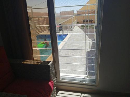 Riḩāb的住宿－شاليه الضياء，滑动玻璃门享有游泳池的景致