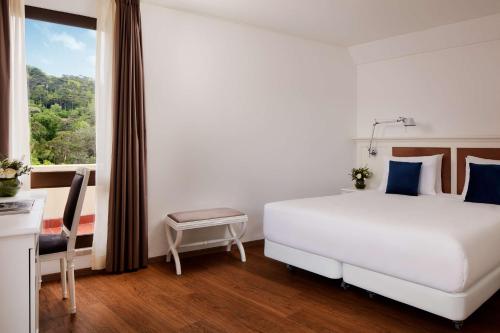 a bedroom with a large white bed and a window at NH Sintra Centro in Sintra