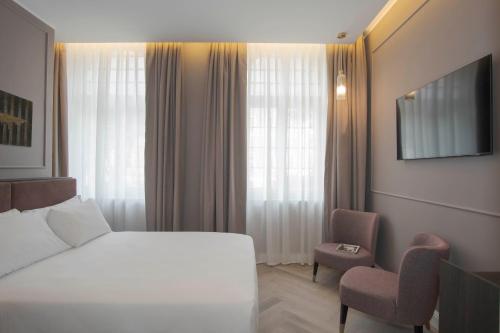 ローマにあるホテル ヴィミナーレのベッドと椅子付きのホテルルーム