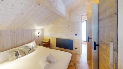 Cette chambre en bois comprend un grand lit blanc. dans l'établissement Chalet Folie, à Peisey-Nancroix