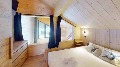 une chambre avec un lit dans une pièce en bois dans l'établissement Chalet Folie, à Peisey-Nancroix