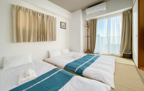 two twin beds in a room with a window at 安楽途 in Tokyo