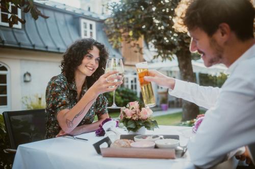 a man and woman sitting at a table drinking beer at Romantik Spa Hotel Elixhauser Wirt in Elixhausen