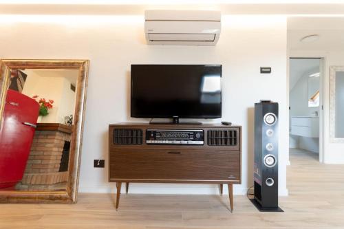 un soggiorno con TV, altoparlante e specchio di Motor Valley PentHouse - B&B Al Caminetto a Modena