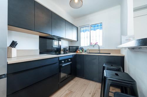- une cuisine avec des placards noirs et un évier dans l'établissement Appartement Le Marly - Happy Rentals, à Antibes