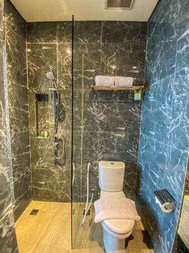 a bathroom with a toilet and a glass shower at Facade Hotel by Azana in Tawangmangu
