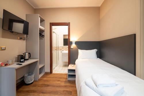 a bedroom with a large white bed and a bathroom at Torino Station Relais in Turin