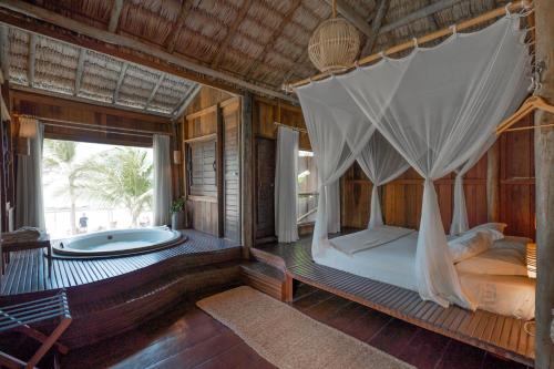 a bedroom with a canopy bed and a tub at Villa Mango in Icaraí