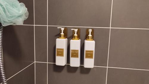 três garrafas de dorizers na parede de uma casa de banho em ESCAL'HOME appart design au pied de l'aéroport, parkings em Blagnac