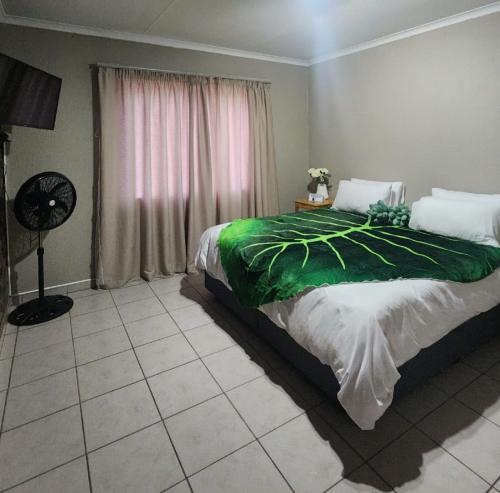 a bedroom with a bed with a green blanket on it at OR Tambo Int Airport Rudman B Self Catering Two Bedroom Home in Boksburg