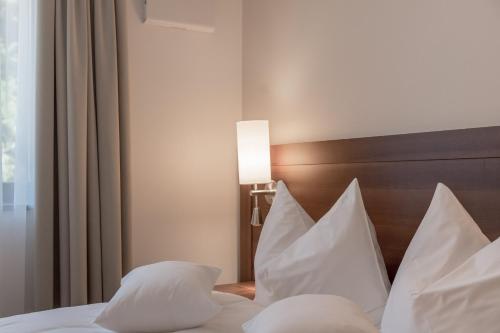 a bedroom with a bed with white pillows and a lamp at Seehotel Restaurant Lackner in Mondsee