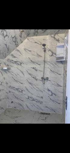 uma casa de banho com uma parede em mármore e um chuveiro em Appartement à 8 mn de mehdia plage em Kenitra