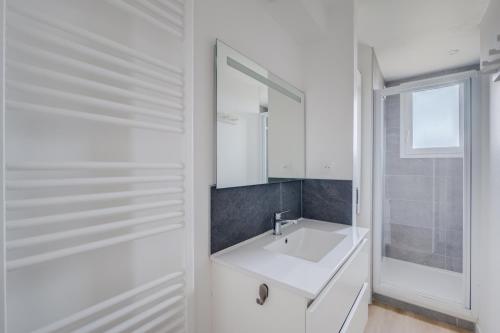 une salle de bain blanche avec un lavabo et un miroir dans l'établissement Mermoz by Yumē, à Toulouse