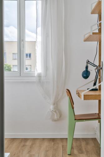 Cette chambre blanche dispose d'une fenêtre et d'une chaise verte. dans l'établissement Mermoz by Yumē, à Toulouse
