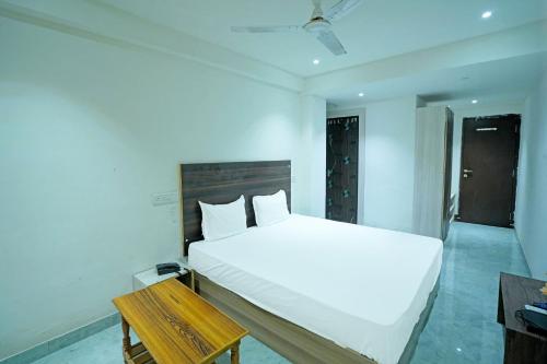 a bedroom with a white bed and a wooden table at OYO SS Palace in Raipur