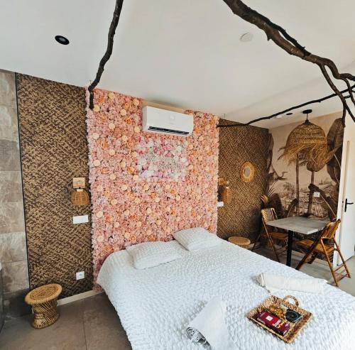 um quarto com uma cama e uma parede coberta de flores em L'expérience LOVE ROOM em Saint-Jean-Bonnefonds