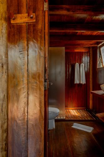 a bathroom with a toilet and a wooden wall at Villa Mango in Icaraí