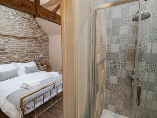 a bedroom with a bed and a glass shower at Meadow Barn in Leominster