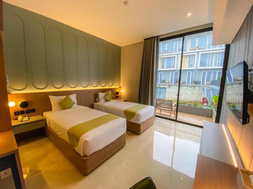 a hotel room with two beds and a large window at Facade Hotel by Azana in Tawangmangu