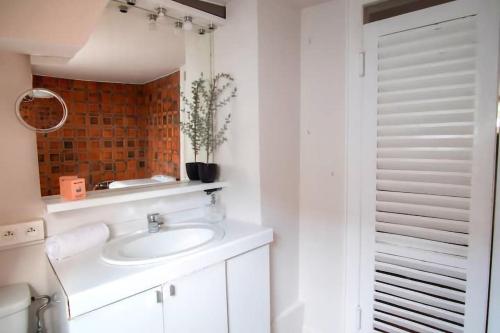 ein weißes Badezimmer mit einem Waschbecken und einem Spiegel in der Unterkunft 8 rue de l'Argile - Studio climatisé in Straßburg