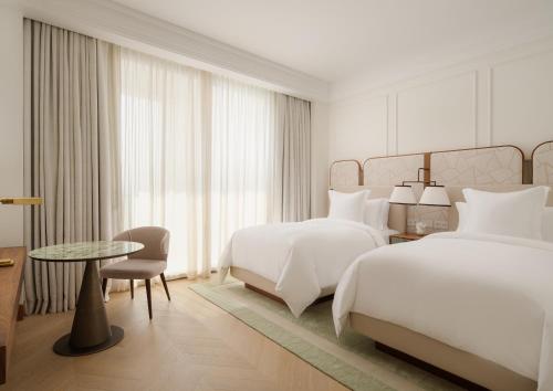 pokój hotelowy z 2 łóżkami i stołem w obiekcie Four Seasons Resort and Residences at The Pearl - Qatar w mieście Doha