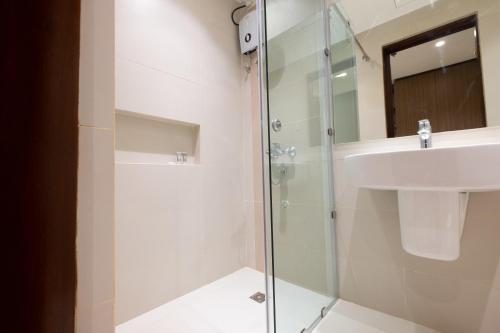 a bathroom with a glass shower and a sink at Soleil Suites Cebu in Cebu City