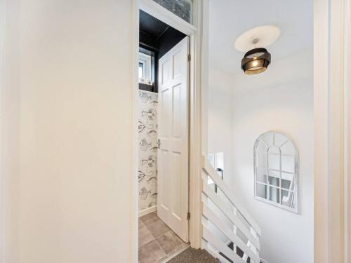 a hallway with a white door and a white staircase at Pass the Keys Unique 3 Bed House in Manchester