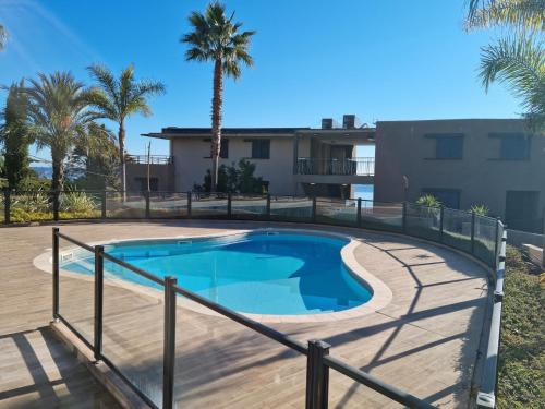 une piscine avec une terrasse en bois et un bâtiment dans l'établissement Infinity - Les Clés de l'Esterel, à Théoule-sur-Mer