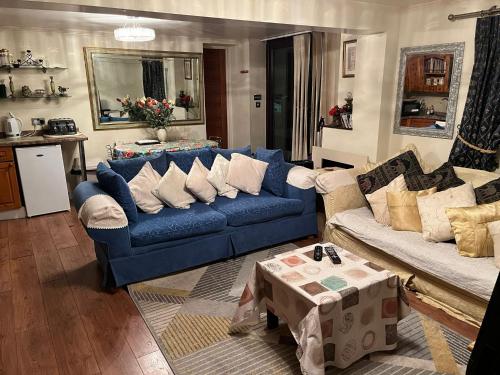 a living room with a blue couch and a table at 2 bedrooms Bell Cottage in Hoddesdon