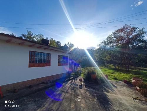 uma vista do sol brilhando sobre uma casa em Buenavista, espacio natural em Ráquira