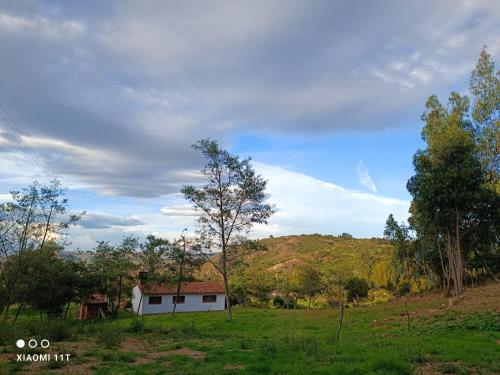 uma pequena casa branca num campo com árvores em Buenavista, espacio natural em Ráquira