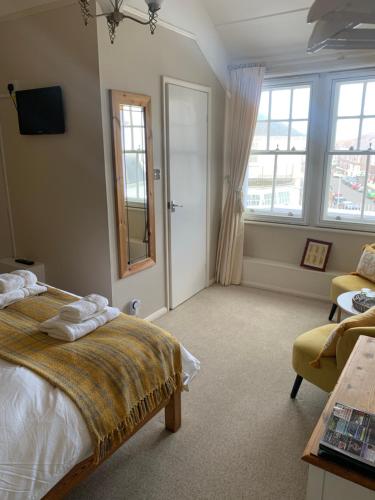 a bedroom with a bed and a couch and windows at Gyves House in Eastbourne