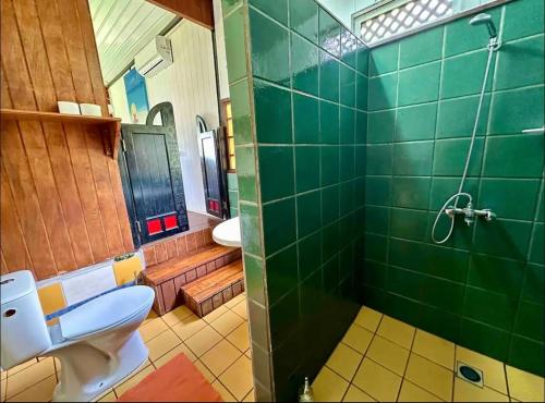 a bathroom with a toilet and a green tiled shower at Fare miti access private white sand beach in Moorea