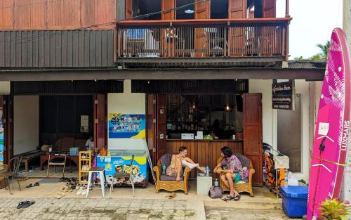 due persone sedute sulle sedie di fronte a un edificio di Aforetime House @ Samui a Taling Ngam Beach