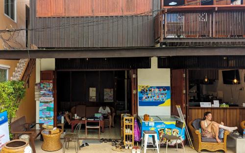 a man sitting in a chair outside of a building at Aforetime House @ Samui in Taling Ngam Beach