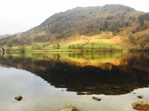 a reflection of a mountain in a body of water at Ghyll Shepherd's Hut in Rydal