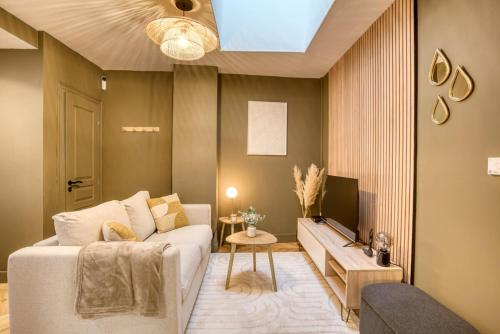 un salon avec un canapé blanc et une télévision dans l'établissement Le France - Les Jardins de Diane, à Fontainebleau