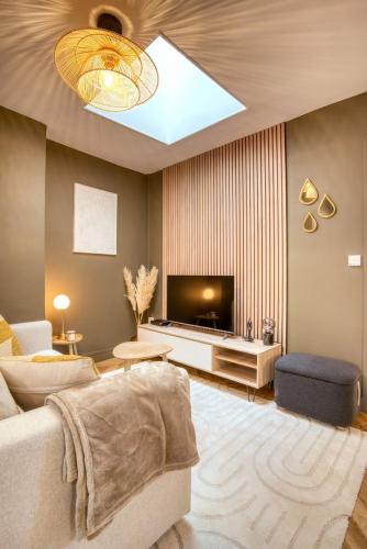 un salon avec un canapé et une télévision dans l'établissement Le France - Les Jardins de Diane, à Fontainebleau