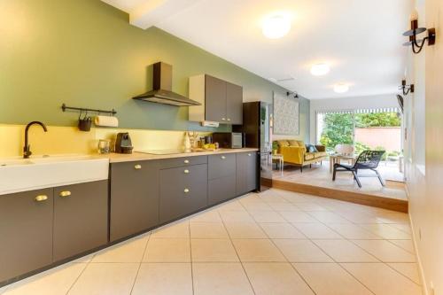 une cuisine avec des placards gris et une salle à manger dans l'établissement La Ruche - Maison 7 chambres et 7 salles de bain, à Fontainebleau