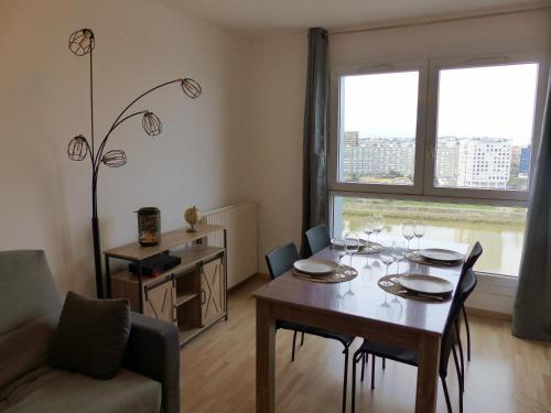 une salle à manger avec une table et des chaises et une fenêtre dans l'établissement VULCAIN 4, 14ème, Ile de Nantes, vue exceptionnelle avec parking, à Nantes