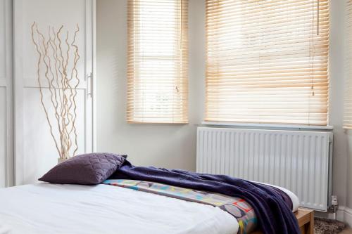 ロンドンにあるMadison Hill - Fernlea Garden 2 - One bedroom homeのベッドルーム1室(ベッド1台付)、ブラインド付きの窓2つが備わります。