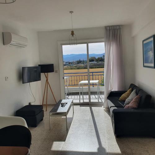 a living room with a couch and a view of a balcony at G&E Harbour Apartments in Lachi