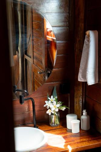 a bathroom sink with a mirror and a vase of flowers at Villa Mango in Icaraí