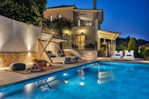 a villa with a swimming pool in front of a house at Ether Villa View in Lithakia