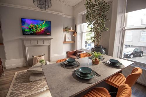 a living room with a table with chairs and a tv at Stunning City Apartment in the Heart of Plymouth in Plymouth
