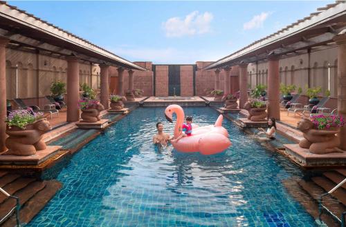 Crowne Plaza Bangkok Lumpini Park, an IHG Hotel في بانكوك: مسبح مع فلامنغو وردي وناس في الماء