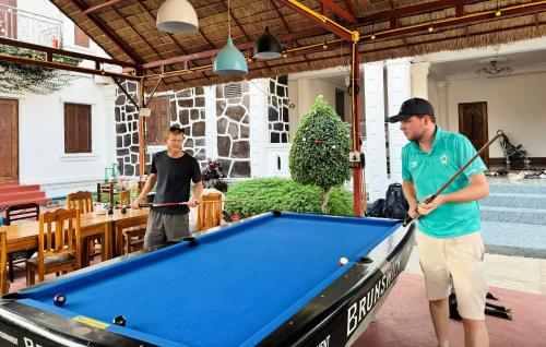 two men playing pool on a pool table at Sabai Sabai Backpackers Hostel in Luang Prabang