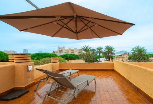 a patio with two chairs and an umbrella on a balcony at Apartamento Dos Mares by Rental Olé in La Manga del Mar Menor
