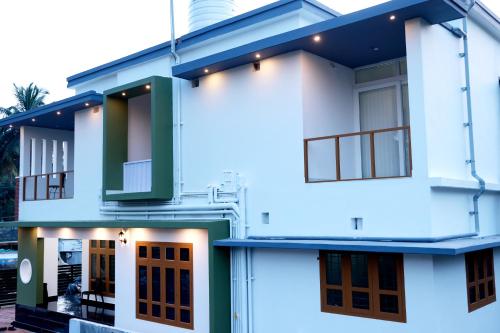 a white house with green doors and windows at Oxygen Home Stay in Agali