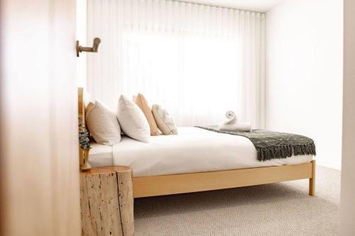 a bedroom with a bed with white sheets and a window at Discover - Ebenezer Bicheno in Bicheno